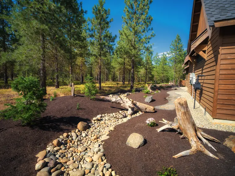 Dry creek bed and driftwood along a timber home
