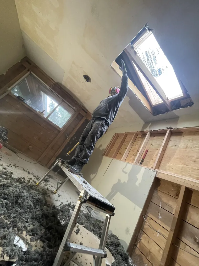 Crew member working on a skylight opening from a ladder, with the walls opened up