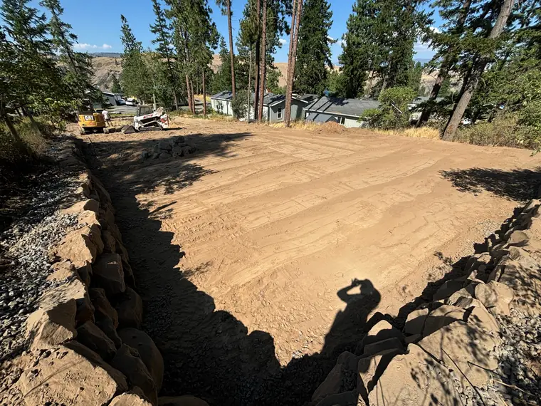 Rockery walls framing a freshly graded, level yard on a hillside