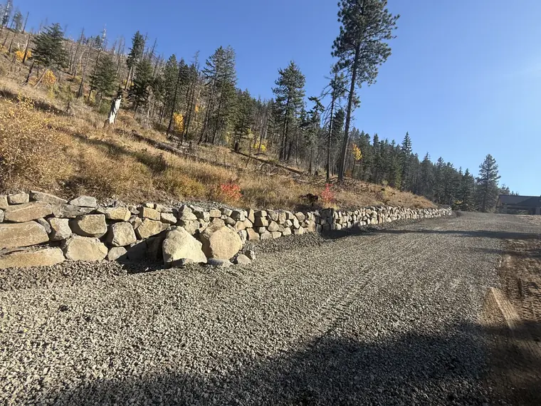 Boulder rockery holding the cut bank along a new gravel driveway in Ronald