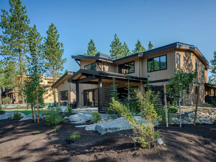 Mulch beds with boulders and young trees across the back of the home