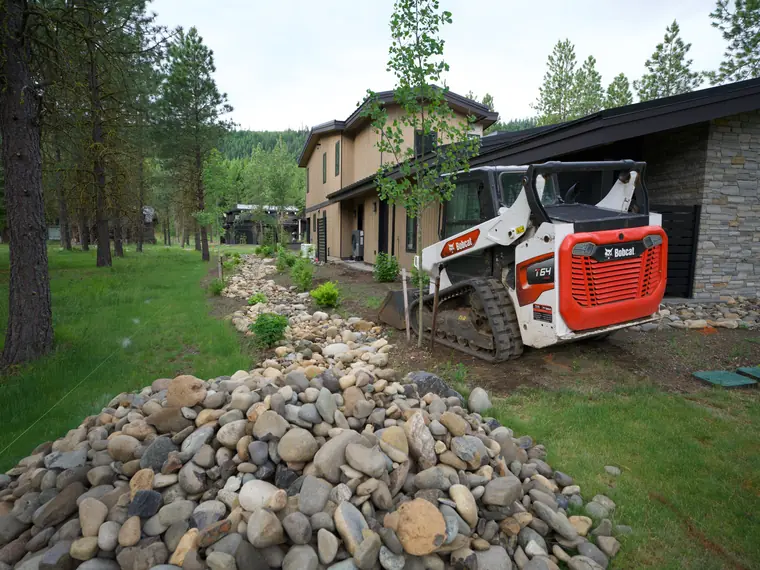 River-rock drainage swale going in beside a new home during the build