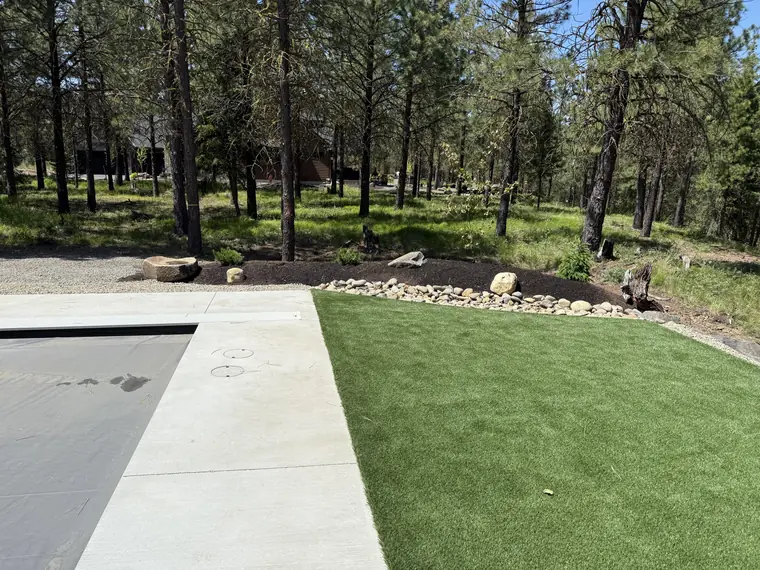 Planted beds framing a stretch of artificial turf next to a pool deck
